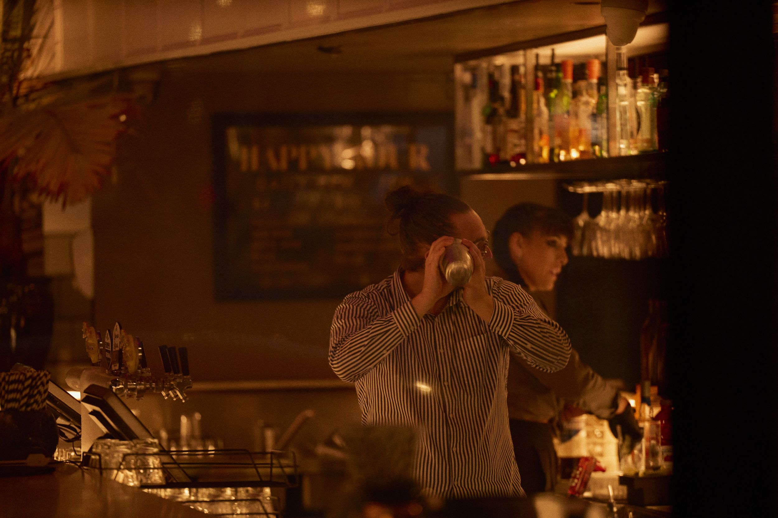 Bartender mixing a cocktail behind a bar.